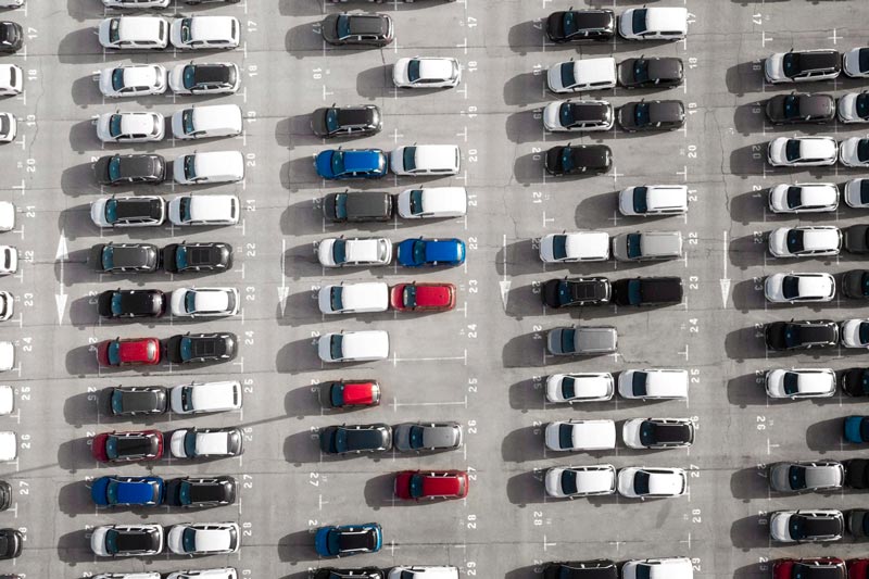 Vogelperspektive auf einen großen Parkplatz bei Gebrauchtwagen Ankauf Geesthacht, der mit Reihen weißer Autos gefüllt ist.